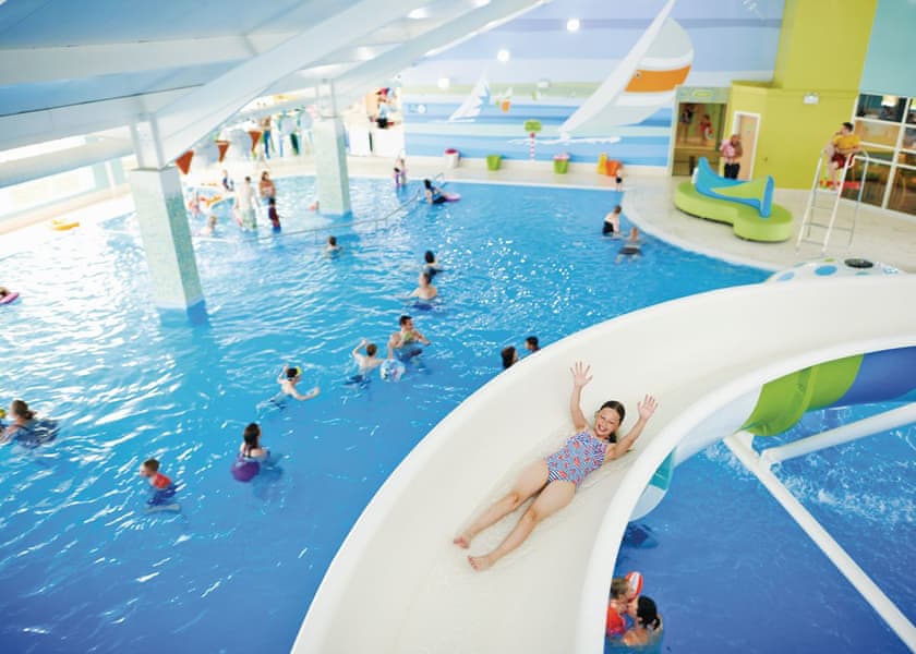 Children using a water slide in a swimming pool at a Yorkshire holiday park