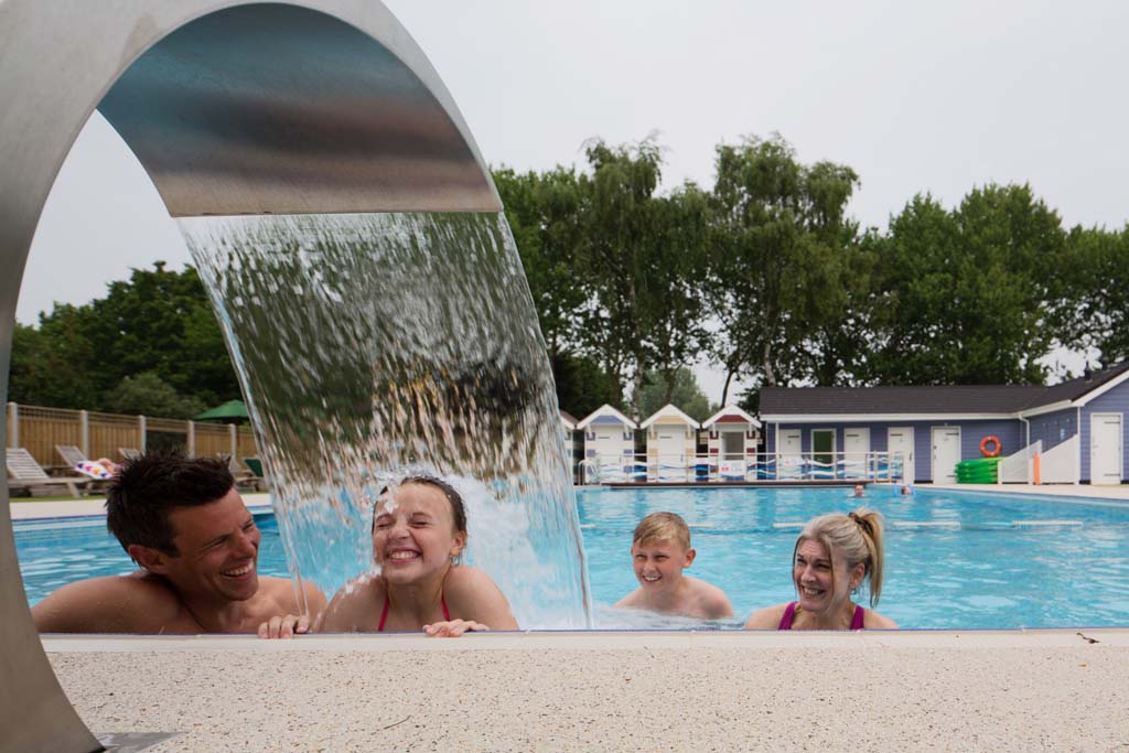 Family enjoying a swimming pool water feature in an accessible caravan park in Norfolk
