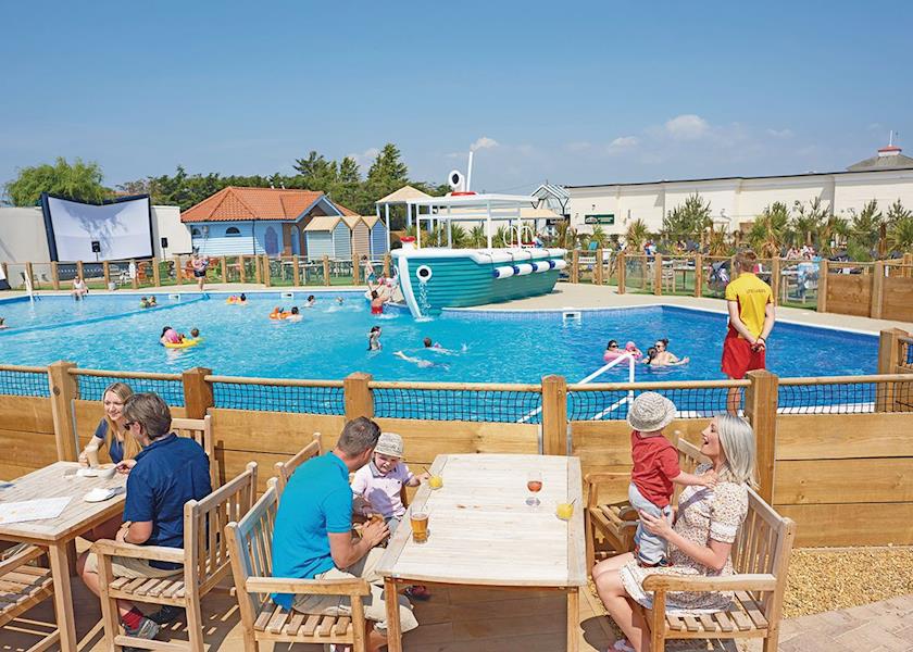 People enjoying the outdoor swimming pool at traditional Essex holiday park