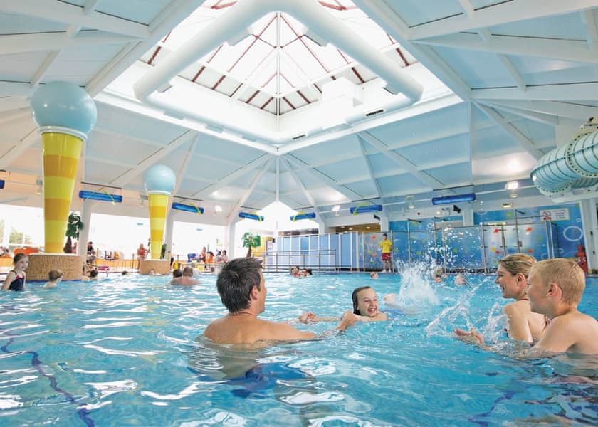 Family swimming in indoor swimming pool at accessible Sussex holiday park