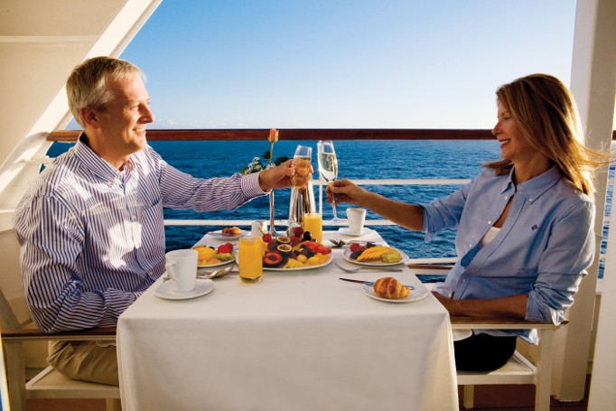 Couple enjoying breakfast and toasting on a cruise