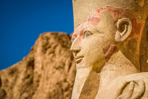 Ancient statue of a pharaoh against a blue sky in Luxor, Egypt