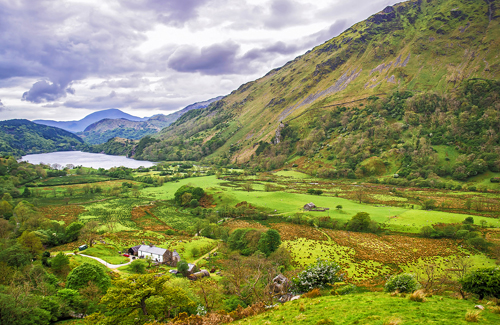 Beautiful scenery of green mountains, a lake, and a cottage in Snowdonia National Park, Wales