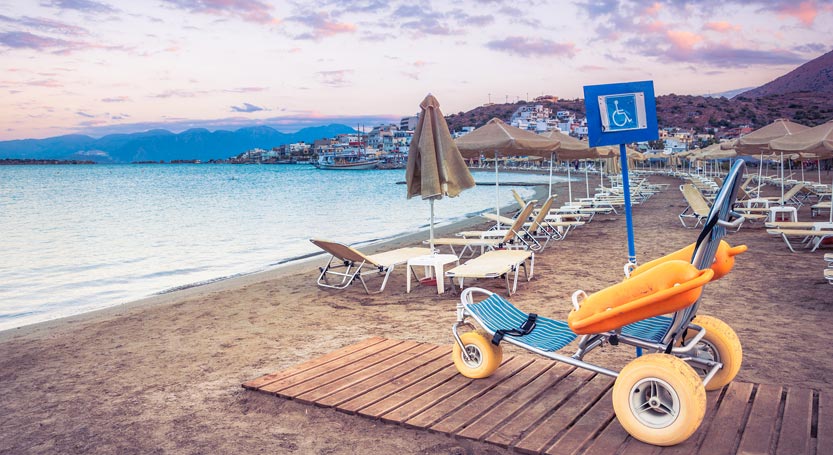 A beach wheelchair on an accessible wooden walkway on a beach in Crete