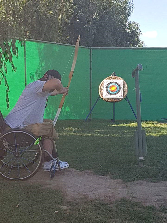 Wheelchair user practising archery on an accessible holiday in Crete