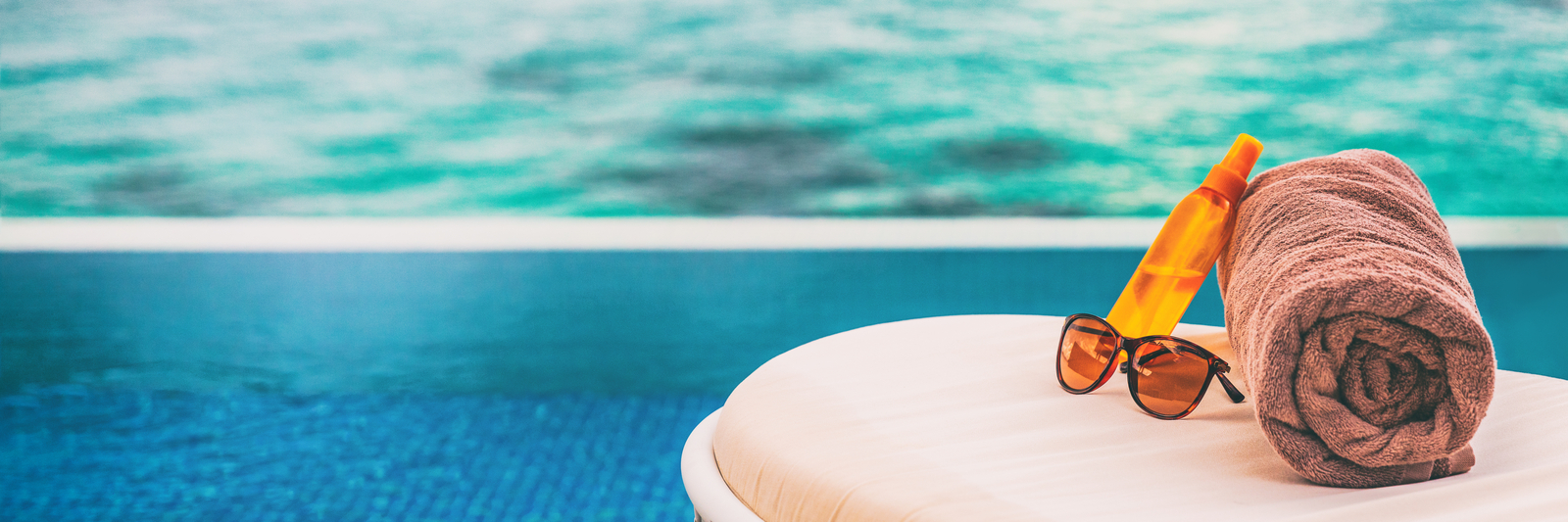 Sunglasses and beach towel next to swimming pool