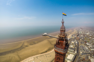 Pride flag atop Blackpool Tower, looking out to the beach