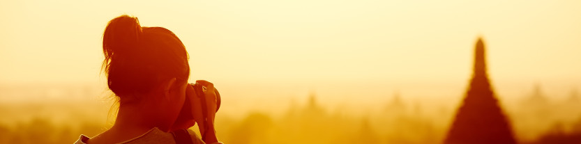 Tourist taking a photograph of an exotic building at sunset